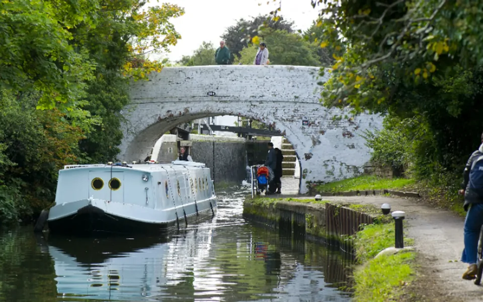 A narrowboat passing beneath a white brick bridge on the Hanwell lock flight